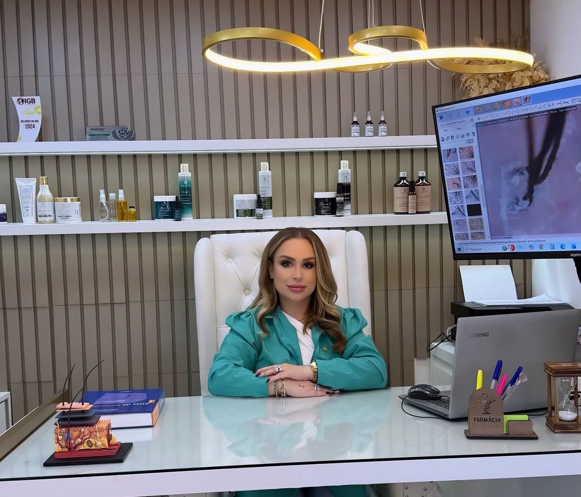 Andri Vargas em seu consultório, com o equipamento de exame de imagem do couro cabeludo ao lado